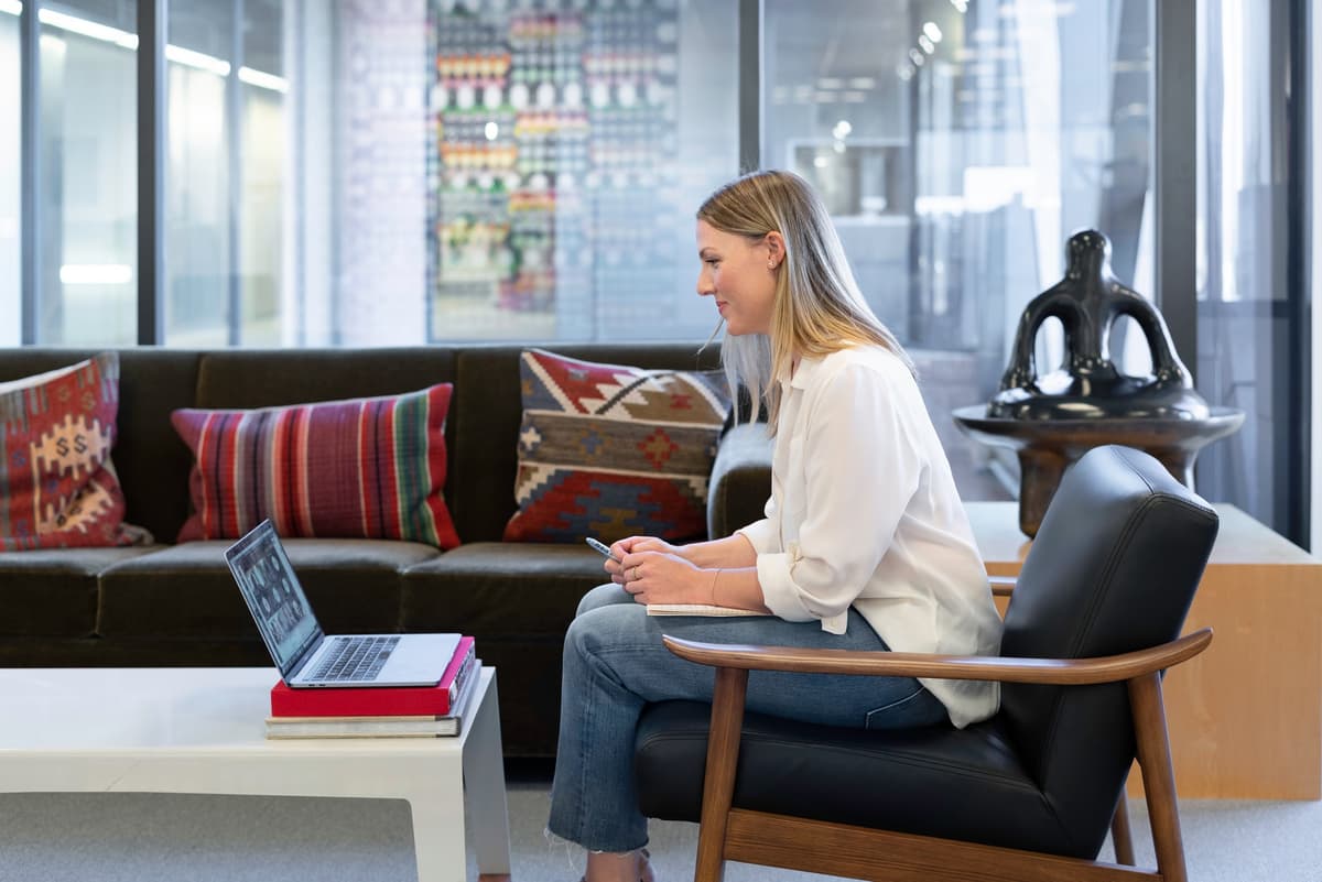 Person sitzt mit MacBook auf einem Sessel